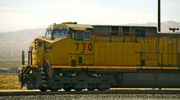 Locomotora color amarillo con azul sobre las vías de tren